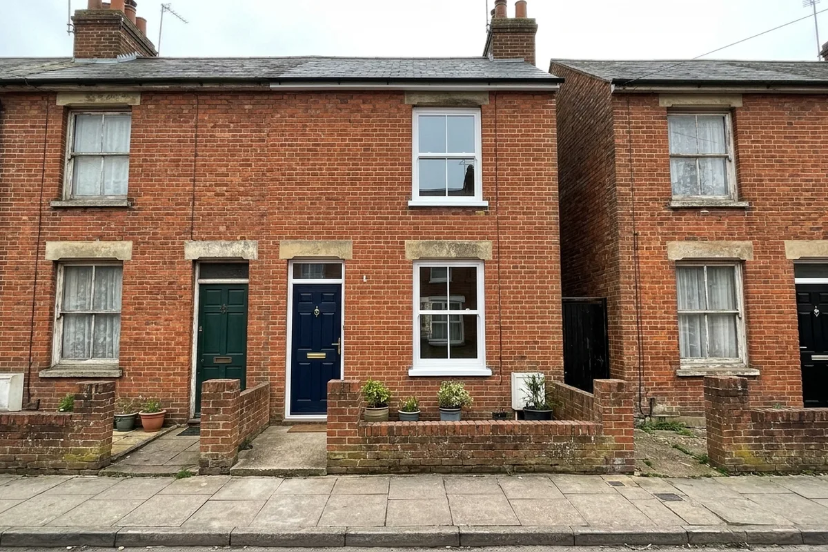 Red brick Victorian terraced cottage with a navy front door and two new white sash windows, one upstairs and one down, between neighbours with older windows
